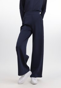 Pantaloni largi bleumarin, cu panouri din dantelă texturată pe laturi. Material moale, cu o finisare netedă. Asortați cu adidași albi.