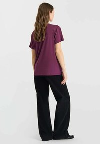 Bordeaux kortemouw T-shirt gecombineerd met zwarte wijde broek, met een ontspannen pasvorm en een soepele textuur. Eenvoudig ontwerp zonder zichtbare patronen.