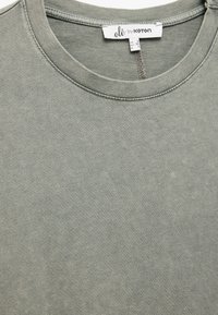 Grøn bomulds T-shirt med rund hals, blød tekstur og et lille mærke ved kraven, der angiver størrelse og mærkedetaljer.