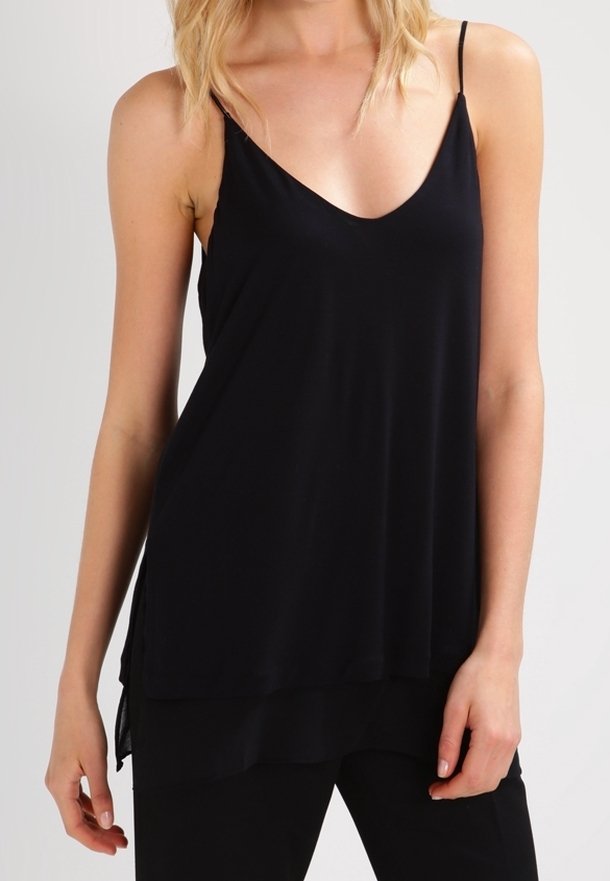 Svart ärmlös topp med V-ringning, tillverkad av mjukt tyg, med en svävande design och lager på lager nederkant för extra längd och rörelse.