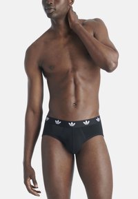 Zwarte katoenen slip met een elastische tailleband, voorzien van witte Adidas trefoil logo's, een gladde textuur en een strakke pasvorm.