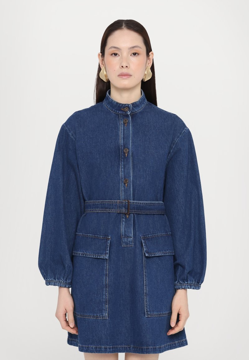 Rochie din denim cu guler înalt, mâneci lungi, volănașe, închidere cu butoane în față, curea la talie și două buzunare aplicate, din material albastru închis.