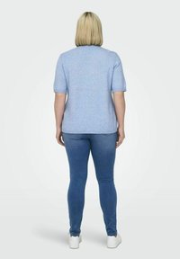 Svetlo modra kratka majica s kratkimi rokavi in okroglim izrezom, v kombinaciji z denim jeansom in belimi športnimi copati. Gladka tekstura, sproščen kroj.