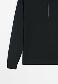 Pullover nero a maniche lunghe con orlo e polsini a coste. Presenta una metà cerniera davanti e una texture a maglia liscia in tutto il capo.