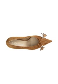 Ballerina in suede marrone con punta a punta, decorata con un fiocco e una nappina sul davanti. L'interno presenta una fodera liscia di colore chiaro.