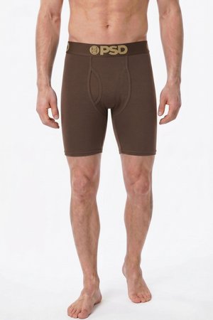 Mannelijke torso en benen in bruine boxershorts met PSD-logo op de tailleband, staand op blote voeten tegen een witte achtergrond.