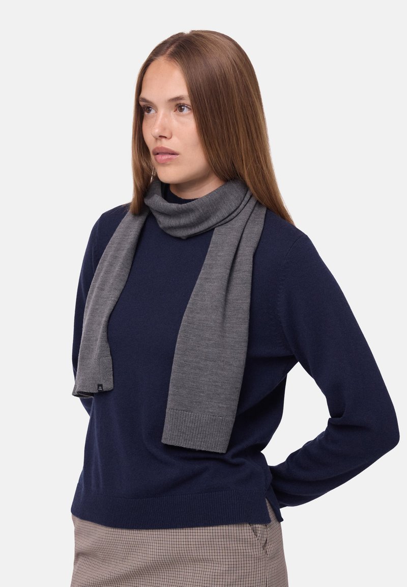 Gray scarf made of soft knit fabric, featuring a ribbed edge. Worn with a navy sweater, showcasing a relaxed drape and smooth texture.