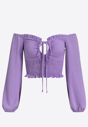 Top court violet, épaule dénudée, manches longues, devant froncé, lien à nouer et accents à volants le long de l'encolure et de l'ourlet.