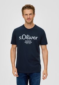 Tamsiai mėlynas medvilninis marškinėliai su apvaliu kaklu, ant kurios priekyje yra balta užrašas „s.Oliver Elevated Essentials Since 1969“.