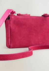 Bolso de hombro de ante rosa con una textura suave, cierre de cremallera y una correa a juego con detalles de costura. Diseño compacto y rectangular.