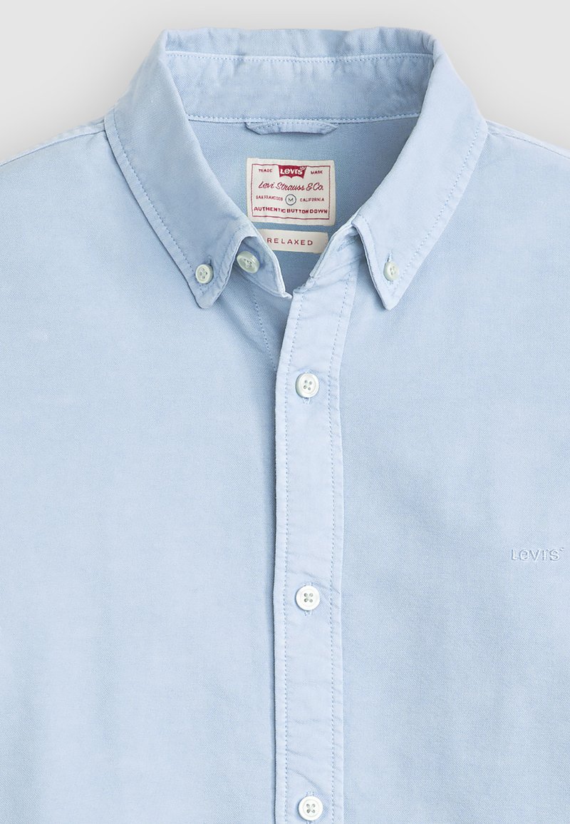 Hellblaues Hemd mit Knöpfen, geknöpftem Kragen, weißen Knöpfen, Levi's-Etikett innen am Kragen und kleinem Levi's-Logo auf der Brust.