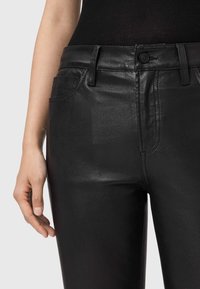 Czarne skórzane spodnie o dopasowanym kroju, teksturowanej powierzchni, przedniej kieszeni i zapięciu na guzik. Gładka powierzchnia z kontrastującym przeszyciem.