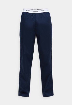 Mornarsko modre hlače z elastičnim pasom, ki ima belo logo trak. Narejene so iz gladkega materiala, s ravnim krojem in brez vidnih žepov.