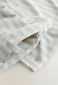 Lightweight fabric in a checkered pattern of pale yellow and gray. Features a textured surface and a small metallic label on the edge.