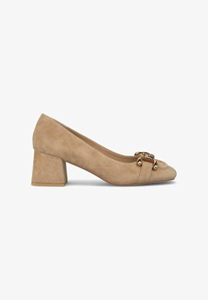 Escarpin en suède beige avec un bout carré et un talon bloc de hauteur intermédiaire. Il présente un accent de boucle en ton doré sur le devant. Texture lisse.