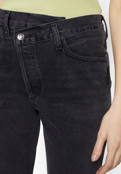 Black denim jeans with a classic fit, featuring front pockets and a smooth texture. Includes a metal button and subtle stitching details.