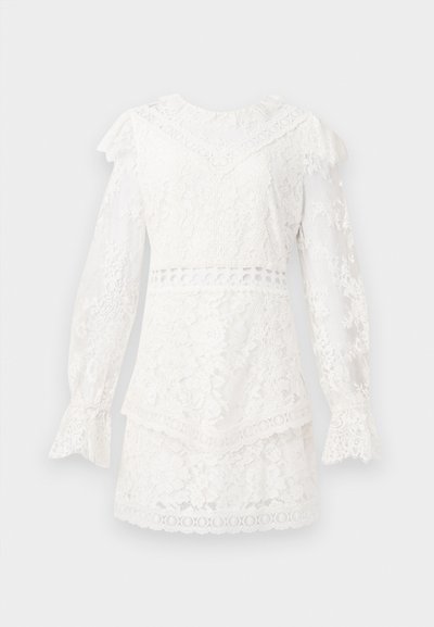 Bijela čipkasta haljina s dugim rukavima, nabranim ovratnikom i manžetama, koja ima složeni dizajn, cvjetne uzorke i okrugle izreze.