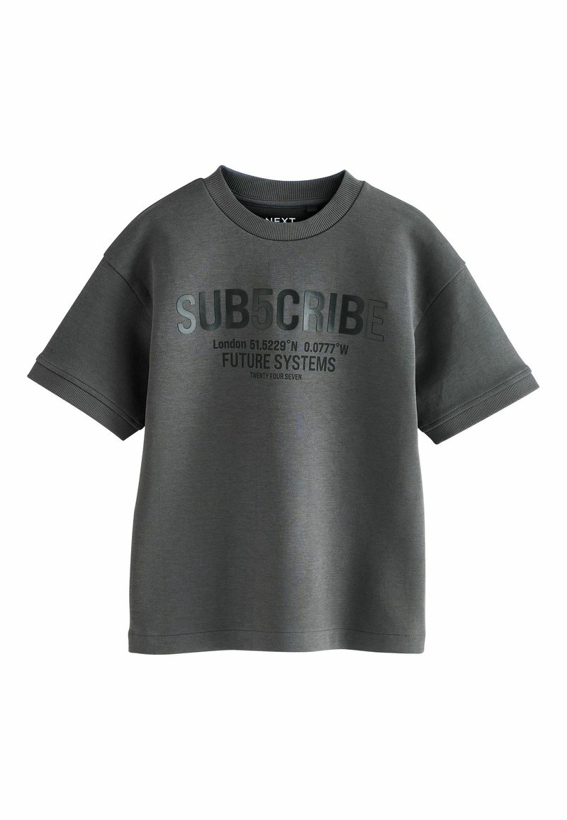 Tricou din bumbac gri, cu mâneci scurte, având un text îndrăzneț negru: "SUB5CRIBE" și coordonate geografice. Guler rotund și croi lejer.