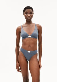 Bralette et string assorti en coton gris, présentant un design en V, des coutures minimales et des étiquettes de marque au centre avant. Texture lisse.