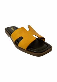 Sanda suave amarilla con un diseño de corte, plantilla acolchada negra y suela de goma marrón. Estilo plano y abierto en la parte delantera.