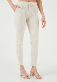 Licht beige, gestructureerde drawstring broek met verticale strepen, voorzien van zijzakken en een tapering pasvorm. Glad materiaal, elastische taille.