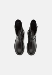 Botas de tobillo de cuero negro con acabado liso, cierre de cremallera en el lateral, punta redonda y suela de goma baja. Sin patrones visibles.