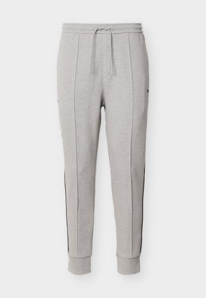Ανοιχτό γκρι στενά παντελόνια φόρμας με ελαστική μέση, κορδόνι, πλαϊνές τσέπες, κάθετες ραφές και ριμπ μανσέτες στους αστραγάλους.