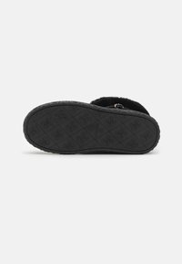 Czarna, futrzana kapcie z teksturowaną gumową podeszwą ozdobioną wytłaczanym wzorem. Posiada ozdobny pasek z metalowym akcentem.
