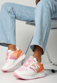 Mångfärgade sneakers med vita, rosa och orange paneler; textilmaterial, snörning och en tjock rosa sula.