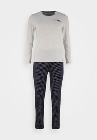 Graues Langarmshirt mit einer Brusttasche und schwarzem Grafikdruck, kombiniert mit navyblauen Punkten-Hosen. Weicher Stoff, figurbetonte Passform und elastischer Bund.