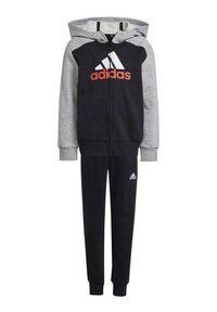 Tuta Adidas in navy e grigio, con una felpa con zip e un logo prominente e pantaloni sportivi abbinati con polsini alla caviglia.