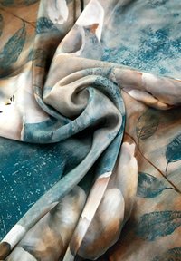 Zijde stof met bloemenpatronen in zachte beige en groene tinten, met een gladde textuur en subtiele variaties in kleur en diepte.