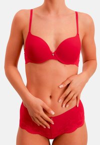 Rotes Dessous-Set mit einem glatten, gepolsterten BH mit verstellbaren Trägern und Spitzenakzenten, kombiniert mit passenden kurzen Höschen mit Spitzenbesatz.