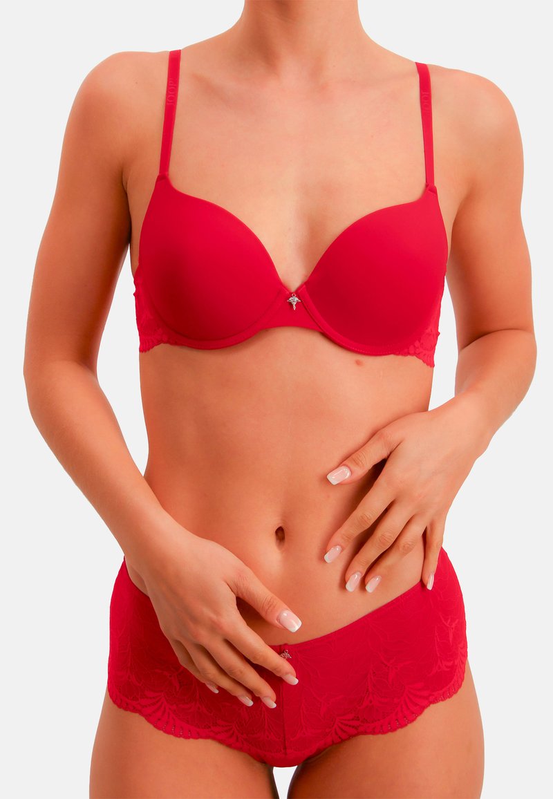 Rotes Dessous-Set mit einem glatten, gepolsterten BH mit verstellbaren Trägern und Spitzenakzenten, kombiniert mit passenden kurzen Höschen mit Spitzenbesatz.