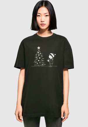 Black cotton t-shirt featuring a white graphic of a child and a Christmas tree, with a star on top and ornaments, in a relaxed fit design.
