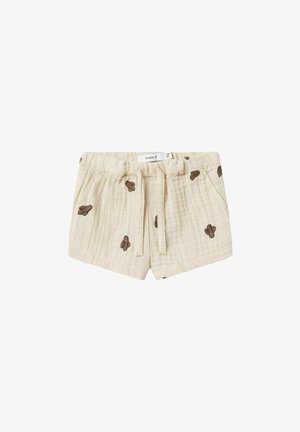 Shorts en coton beige avec une finition texturée, ornés d'une broderie de cactus marron, dotés d'une taille élastique et d'un cordon de serrage pour l'ajustement.