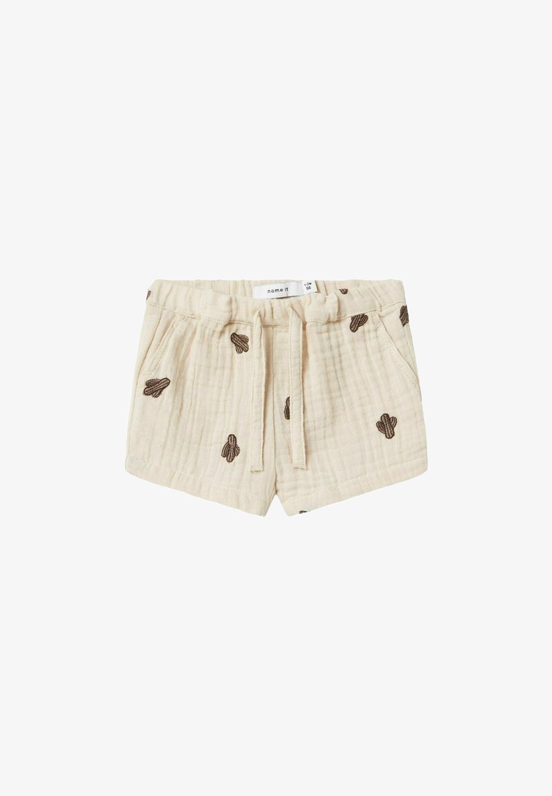 Shorts en coton beige avec une finition texturée, ornés d'une broderie de cactus marron, dotés d'une taille élastique et d'un cordon de serrage pour l'ajustement.