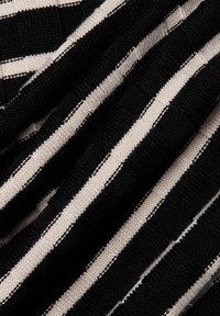 Black and cream striped fabric with a textured weave. The stripes vary in width, creating a contrasting pattern.