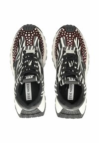 Schwarz-weiße, zebra-gestreifte Sneaker mit einem kastanienbraunen Akzent, verziert mit silbernen Nieten, Schnürsenkeln und einer gemusterten Sohle. Markenlabel sichtbar.
