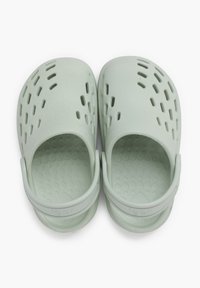 Lysgrønne plastklipklapper med lukket tå, ventilationshuller og en bagrem. Teksturerede indersåler med hævede cirkulære mønstre.