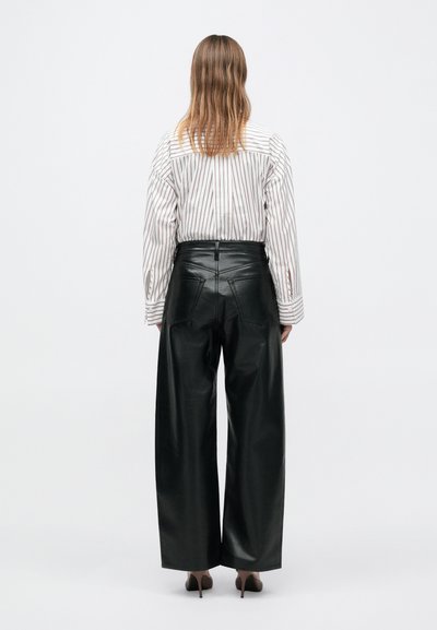 Mustad nahast laia säärega püksid kõrge vöökohaga, sileda tekstuuri ja kohandatud tagataskutega; kombineeritud triibulise pika varrukaga särgiga.