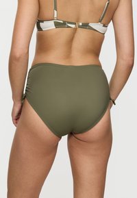 Hochgeschnittener Bikiniunterteil aus olivgrünem Stoff mit glatter Textur. Verfügt über verstellbare Seitenschnüre und nahtlose Kanten für zusätzlichen Komfort.