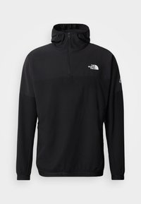 Μαύρο πουλόβερ  με φερμουάρ, φτιαγμένο από ελαφρύ υλικό, με ψηλό γιακά, μακριά μανίκια και μικρό λογότυπο στο στήθος.