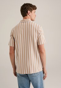 Camisa de manga corta en beige con rayas verticales blancas, con cuello y una tela texturizada. La parte trasera es lisa con un dobladillo curvado.