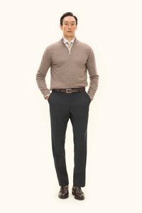 Maglione zip-up marrone chiaro sopra una camicia con colletto, abbinato a pantaloni scuri e su misura e scarpe in pelle marrone. Design semplice e colori neutri.