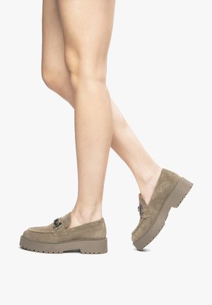 Mocassini beige in suede con suola spessa. Presentano una fibbia decorativa e dettagli texture sulla parte superiore. Design a profilo basso.