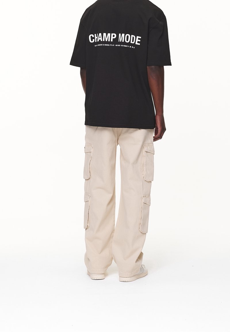 T-shirt noir avec le texte blanc "CHAMP MODE" au dos ; pantalon cargo beige clair avec poches latérales ; coupe décontractée ; en coton.
