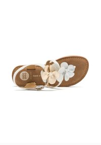 Sandalia blanca con acentos florales en beige y azul, con una plantilla marrón texturizada y correa ajustable en el tobillo.