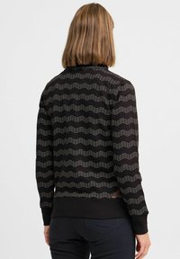 Felpa nera con motivo a zigzag in argento, polsini a costine e tessuto testurizzato. Include un piccolo etichetta sull'orlo.