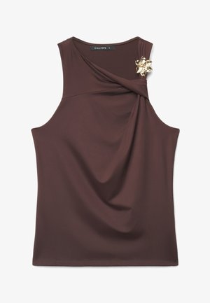 Blouse sans manches marron foncé avec un décolleté drapé et une broche florale dorée épinglée près de l'épaule.